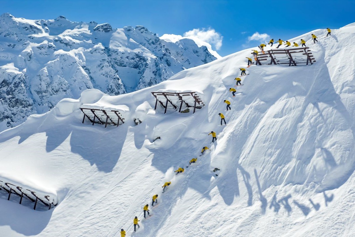 Thomas Feurstein fährt auf dem Snowboard einen schneebedeckten Hang hinunter, im Hintergrund Gebirge