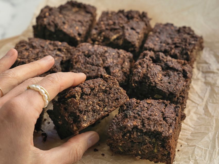 Eine Hand greift auf eine Reihe Schoko-Brownies zu.