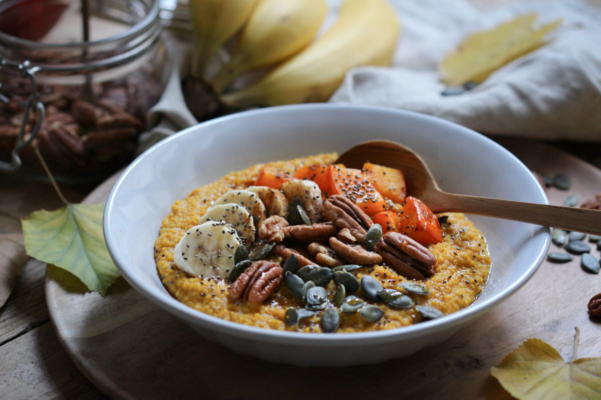 Porridge in einer Schale, angerichtet mit Kürbis, Pekannüssen, Banane und Kürbiskernen